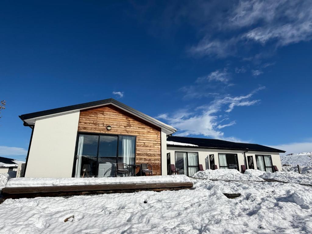 a house with snow on the ground in front of it at Matariki Star in Lake Tekapo