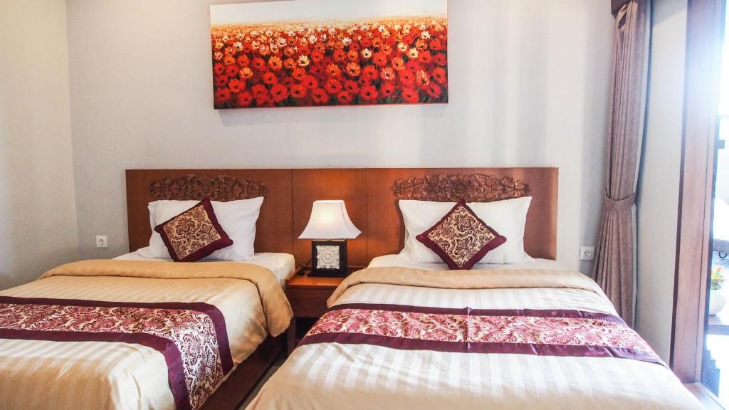 two beds in a room with a painting on the wall at Lebak Nelayan in Canggu