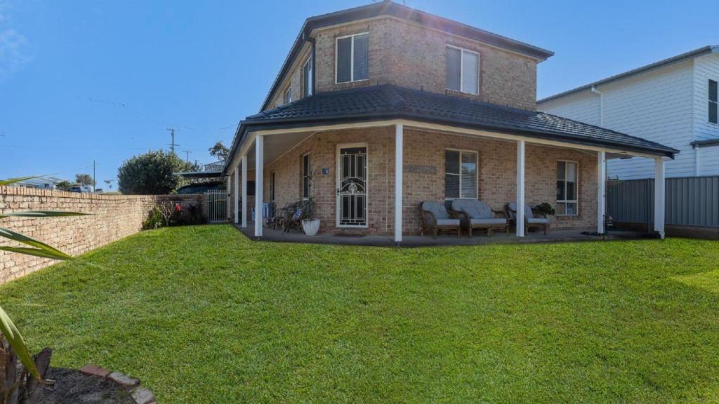 a brick house with a lawn in front of it at Yamba Beach House - Lifestyle Yamba in Yamba