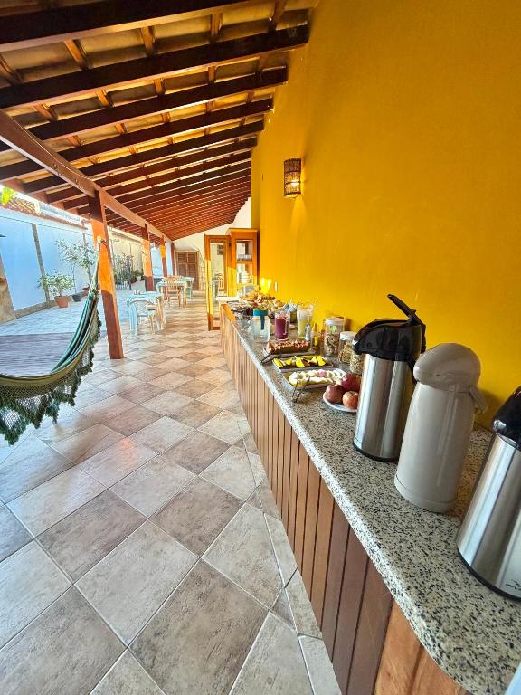 a kitchen with yellow walls and a counter with food at Cantinho Centro Histórico in Paraty