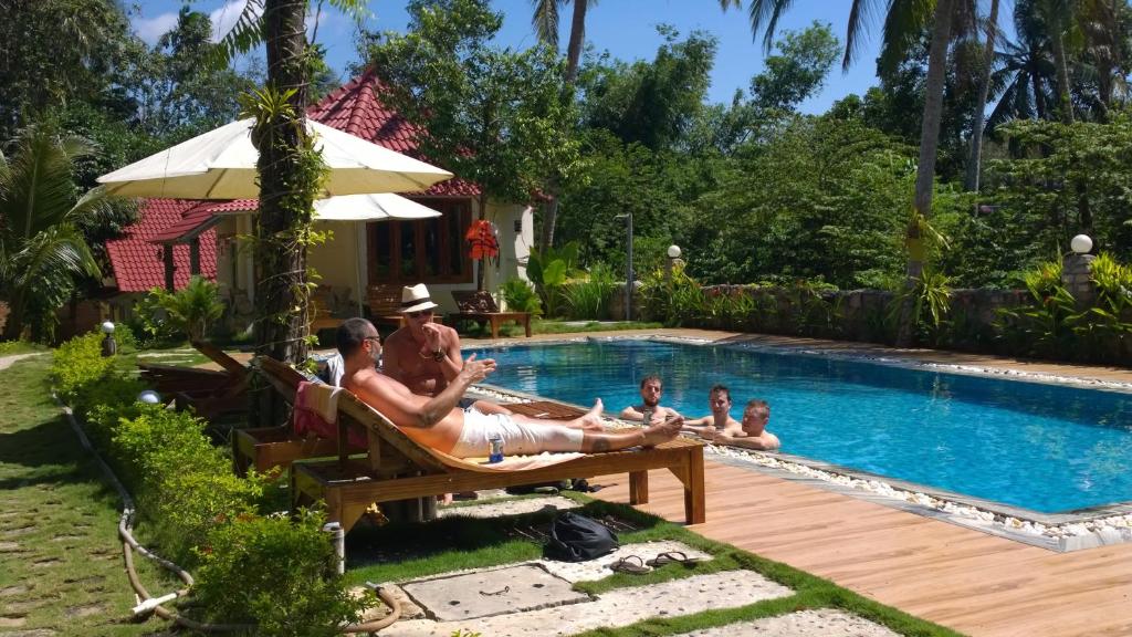 a group of people laying in chairs by a pool at Sun & Wind Paradise Bungalow in Phú Quốc