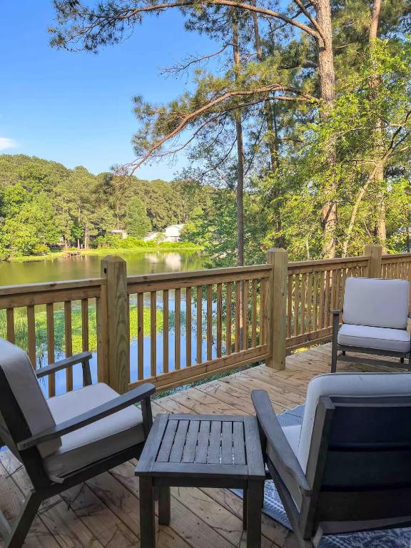 two chairs and a table on a deck with a lake at Big Bass Bungalow - Quitman Tx in Quitman