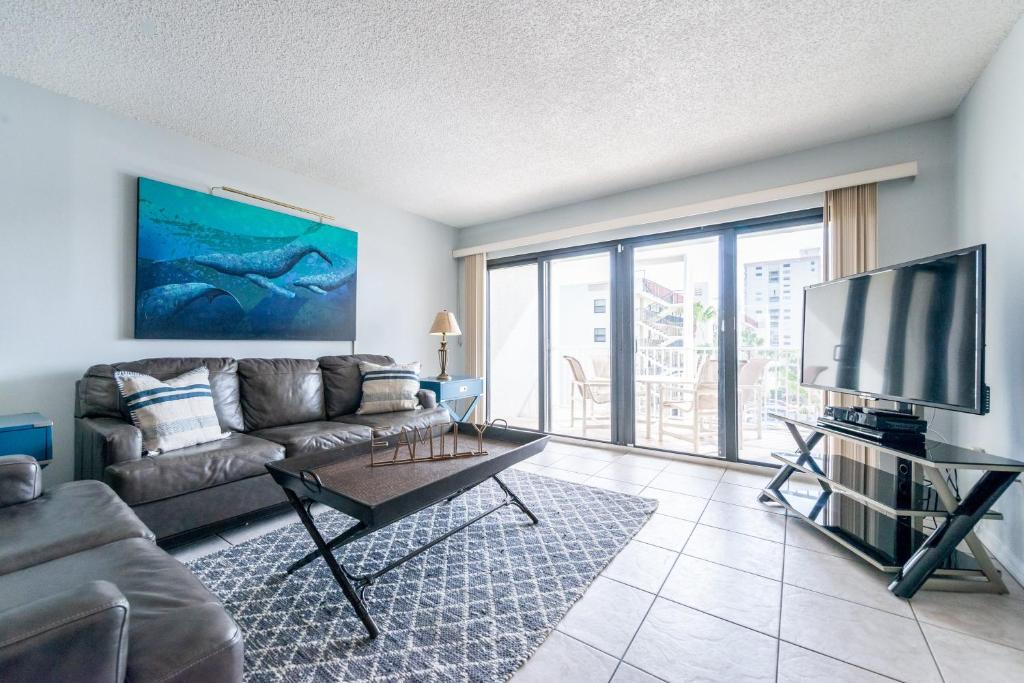 a living room with a couch and a flat screen tv at Sandcastles - Cocoa Beach Oceanfront Condos with Heated Pool Tennis in Cocoa Beach