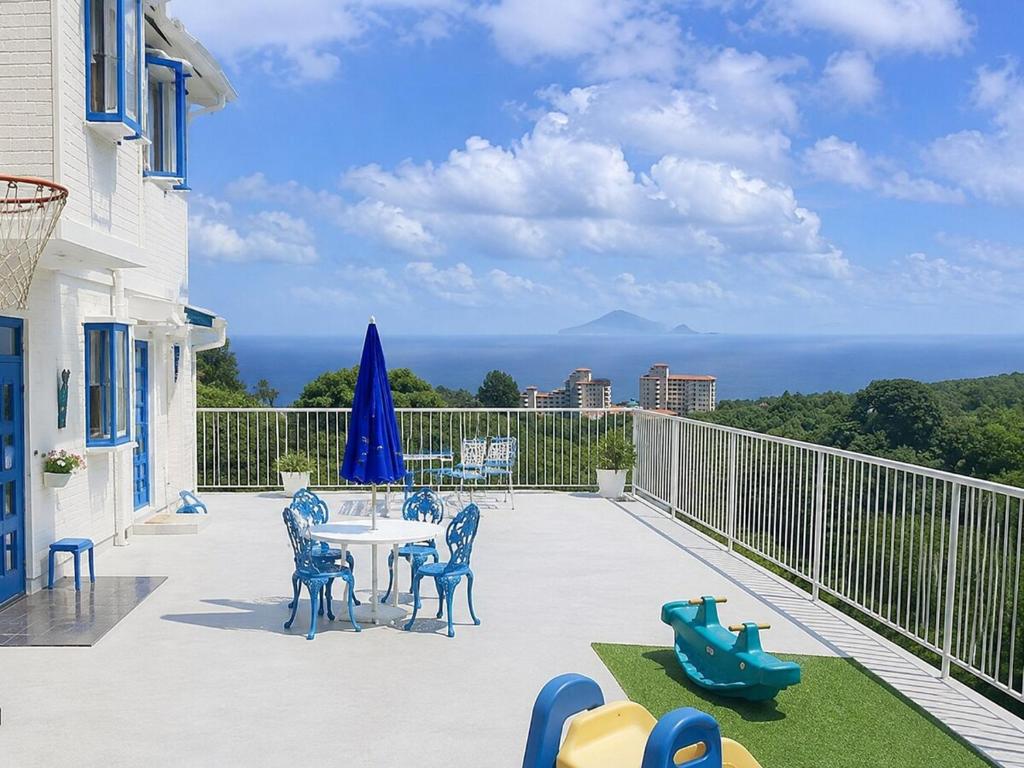 a patio with a table and chairs on a balcony at Villa Knossos in Higashiizu