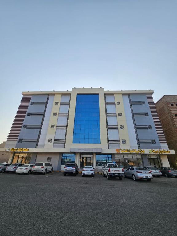 a large building with cars parked in a parking lot at فندق الضيافة in Abu Arish