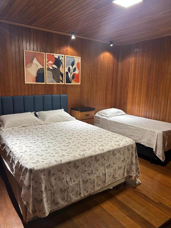 a bedroom with two beds and wooden walls at Éden jardim in Guarapuava