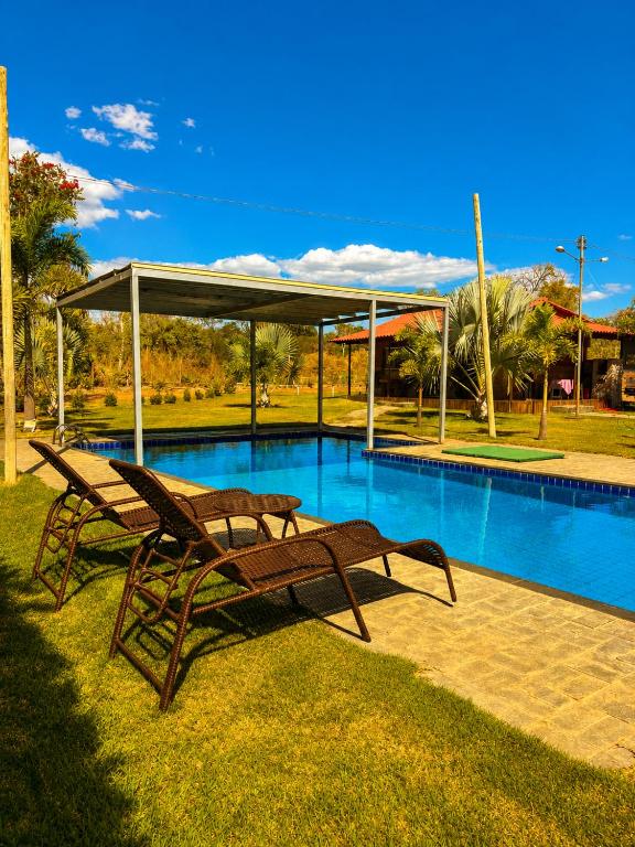 a couple of benches sitting next to a swimming pool at Chalés Araras do Vale in Colinas Do Sul