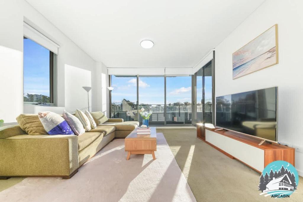 a living room with a couch and large windows at Asquith 2BR Apt Secure Underground Parking in Asquith