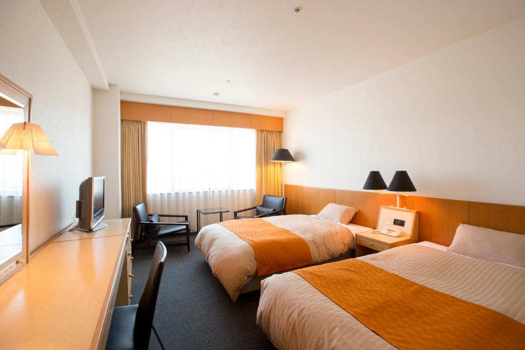 魚津市にあるホテルグランミラージュのベッド2台とテレビが備わるホテルルームです。