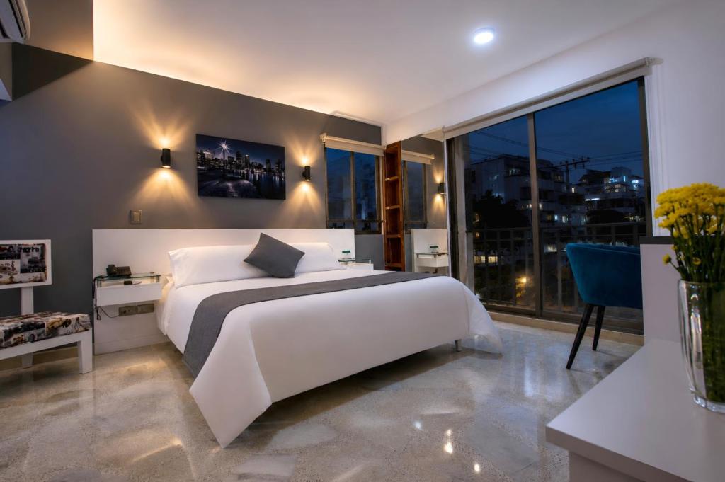 a bedroom with a white bed and a large window at Hotel Casa Esmeralda in Cali