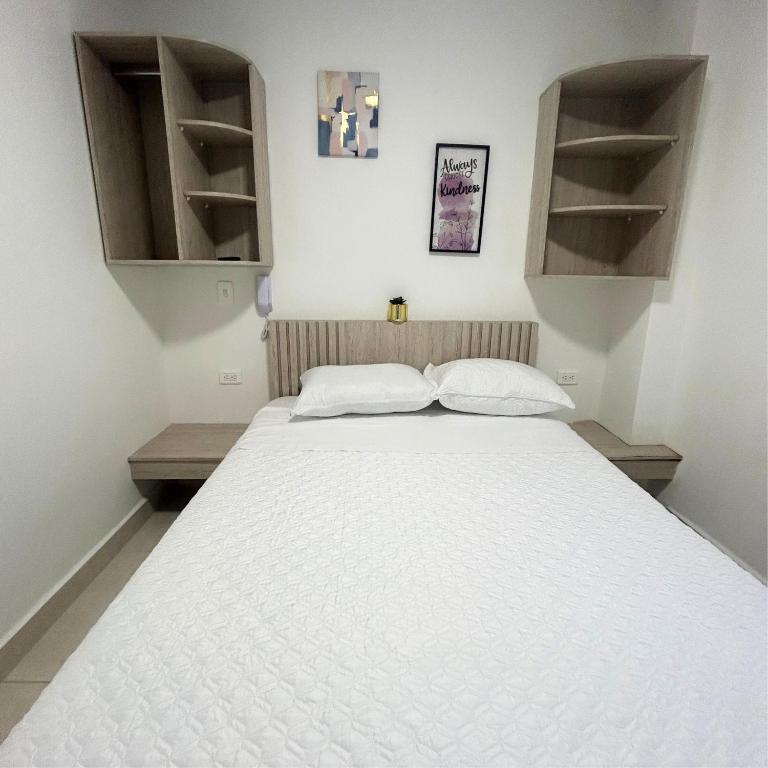 a white bed in a room with open shelves at Hotel Zona Oro in Armenia