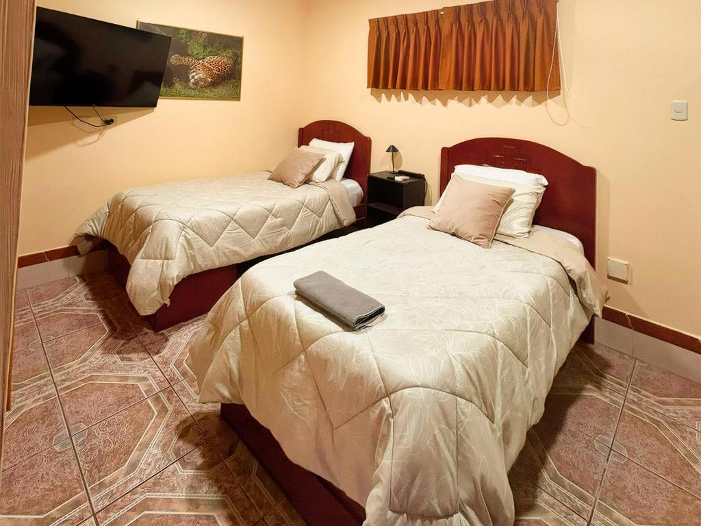a hotel room with two beds and a tv at Casa del Jaguar in Iquitos