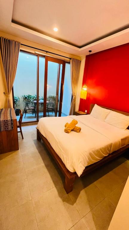a bedroom with a large bed with a red wall at Jalak Merah in Canggu