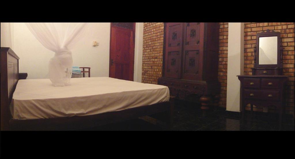a bedroom with a bed and a dresser and a mirror at Hikka Urban Stay in Hikkaduwa