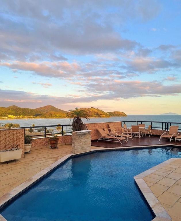 a swimming pool with a view of the ocean at Flat Beira Mar Caraguatatuba in Caraguatatuba