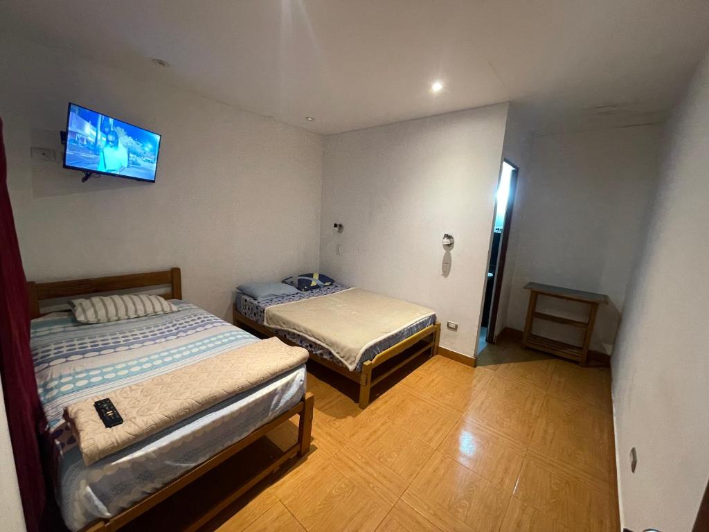 a room with two beds and a tv on the wall at Hospedaje vista del sur paracas in Paracas