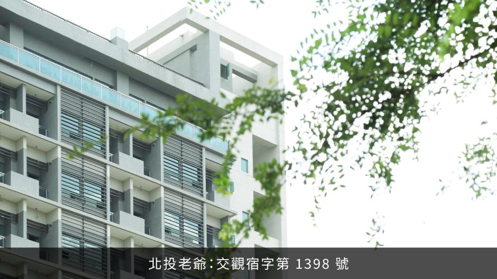 a white building with windows and a tree at Hotel Royal Beitou in Taipei