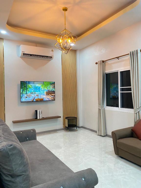 a living room with a couch and a tv at Rose & Nainee House Hatyai in Ban Tha Thon