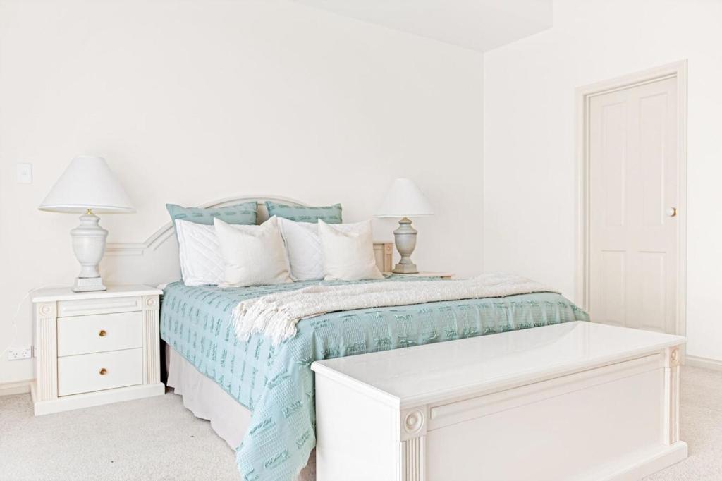 a white bedroom with a bed and two lamps at The Stately Way in Wallaroo
