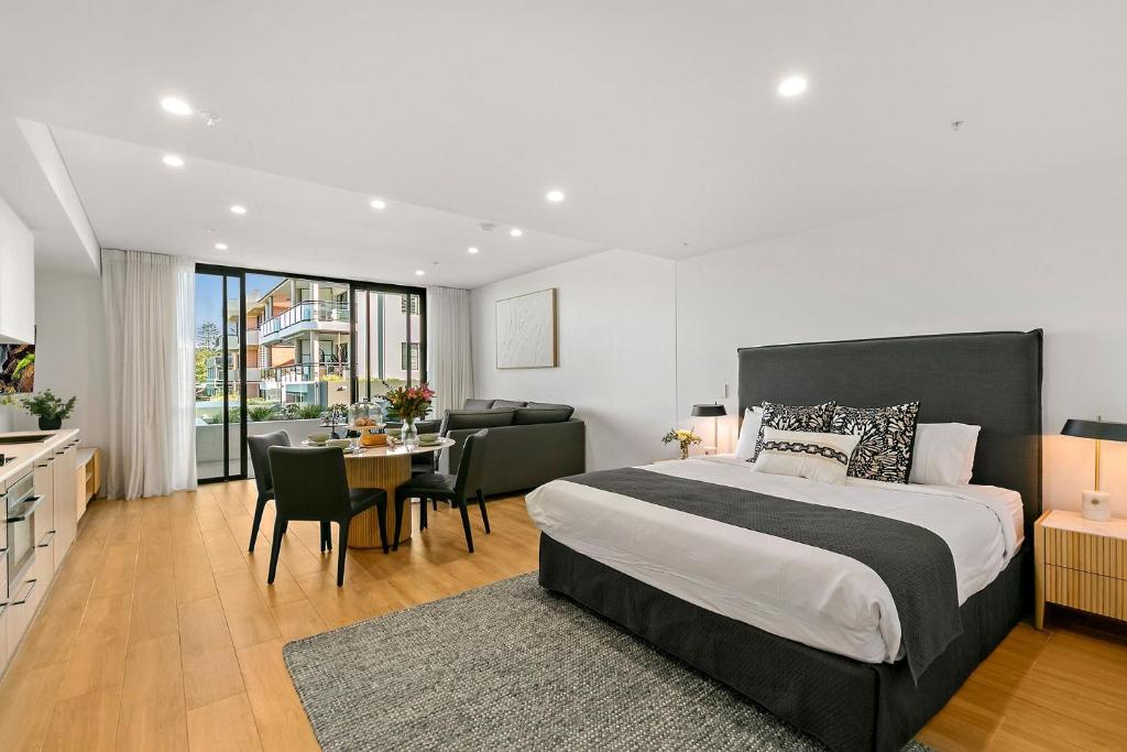 a bedroom with a large bed and a table with chairs at Kove Apartment - G03 in Kiama