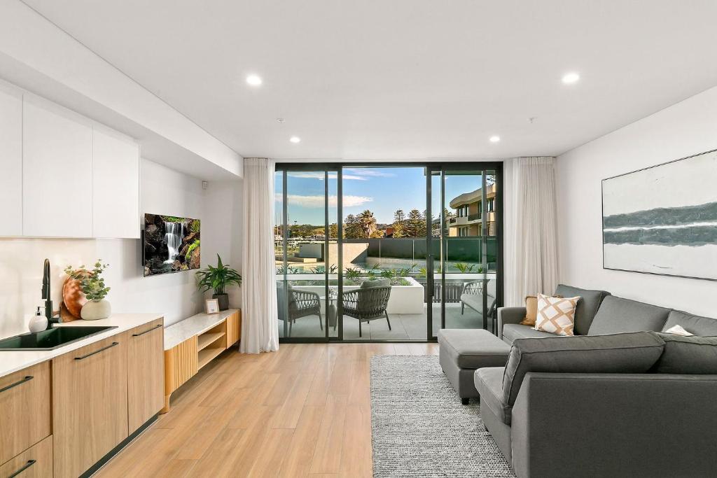 a living room with a couch and a kitchen with a view at Kove Apartment - G05 in Kiama