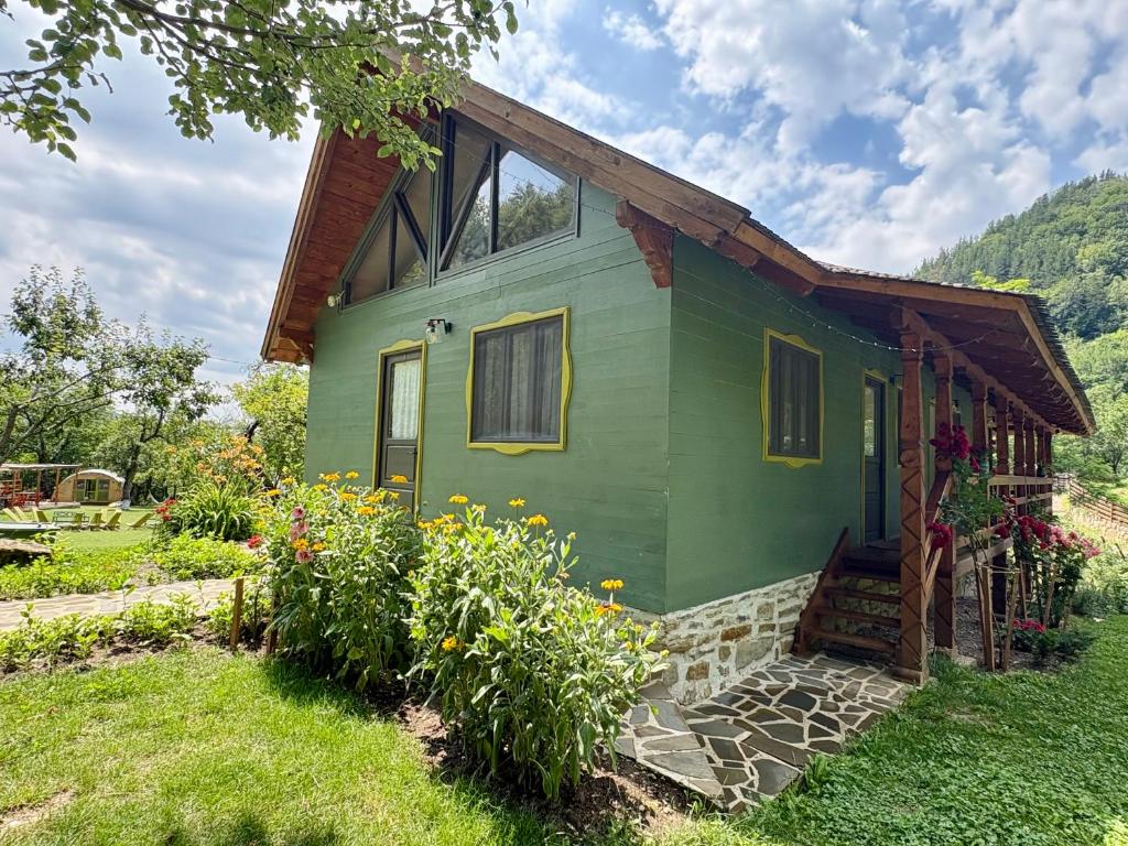 a green house with flowers in front of it at Alunis RETREAT in Aluniş