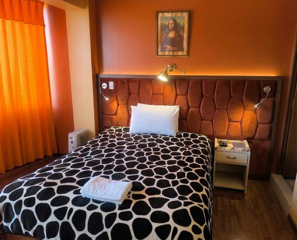 a bedroom with a bed with a black and white comforter at Andenes Puno in Puno
