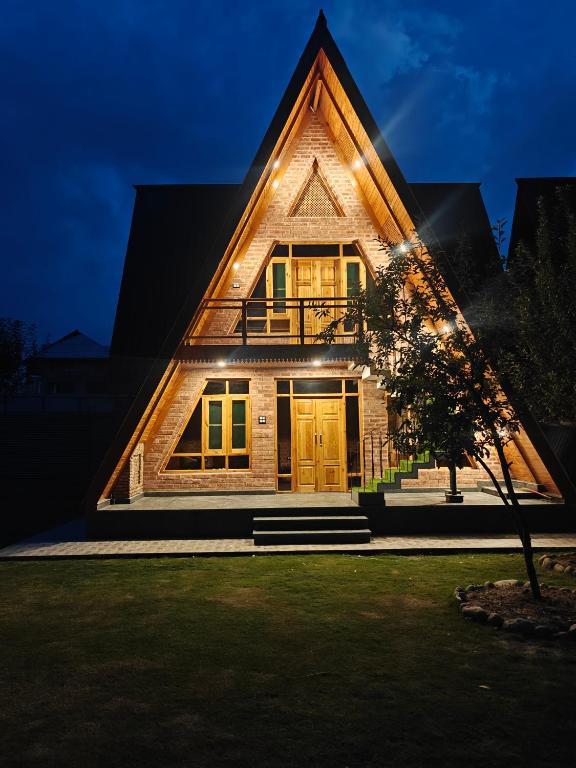 a house with a triangle roof with the light shining on it at French Woods Cottages in Srinagar