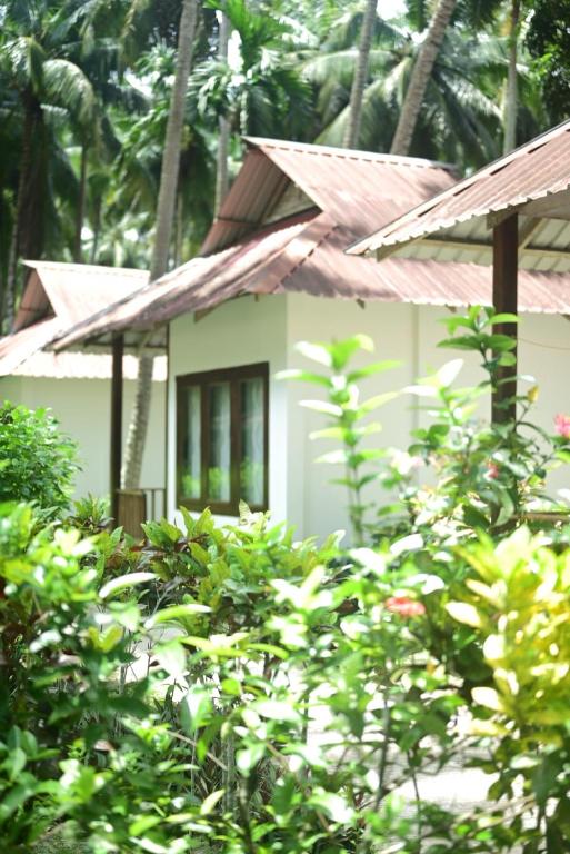 a small white house with a rusty roof at Cross Bill Beach Resort in Havelock Island