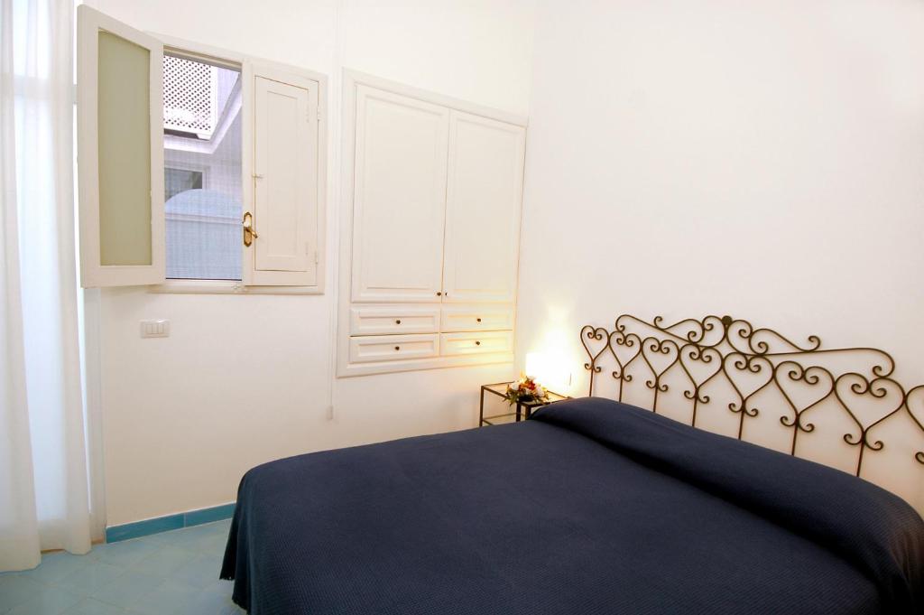 a bedroom with a bed with a blue bedspread and a window at Hotel Aurora in Amalfi