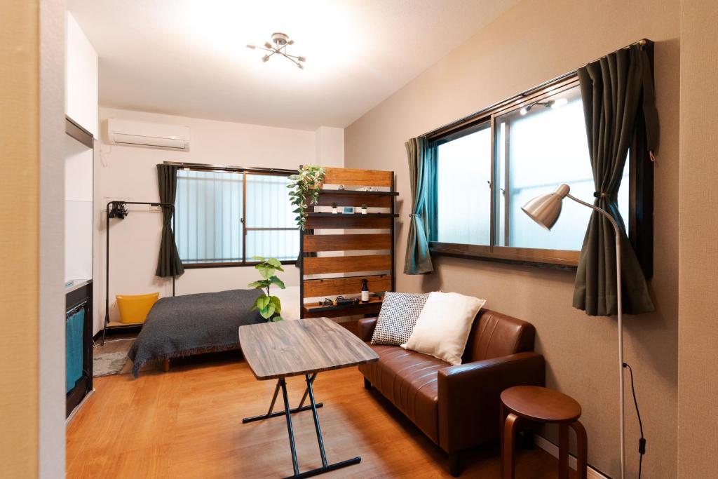 a living room with a couch and a table at Osaka Petite Tanuki Inn Neyagawa in Neyagawa