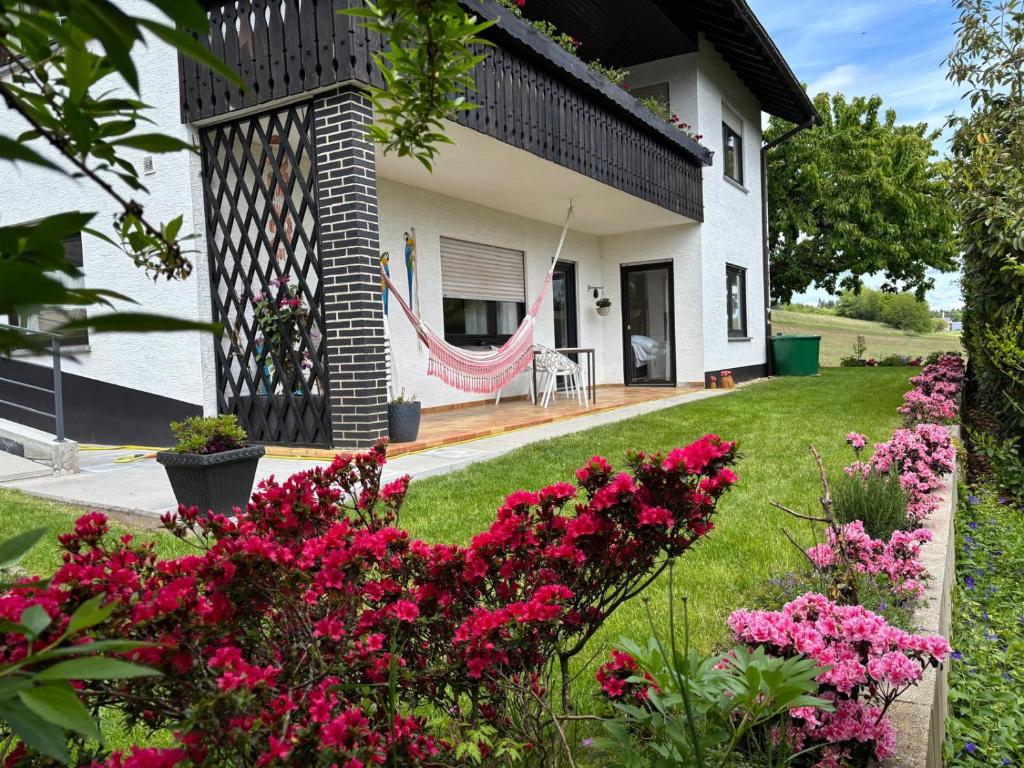 a house with pink flowers and a hammock in the yard at Familienglück im Odenwald in Grasellenbach