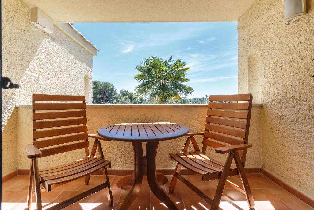 two chairs and a table on a balcony with a palm tree at Apartments Bellevue Plava Laguna in Poreč