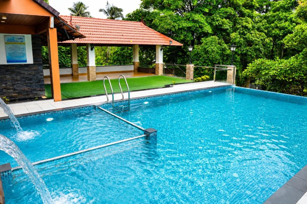 a large swimming pool with a water fountain at Athirappilly Rainland Resort in Athirappilly