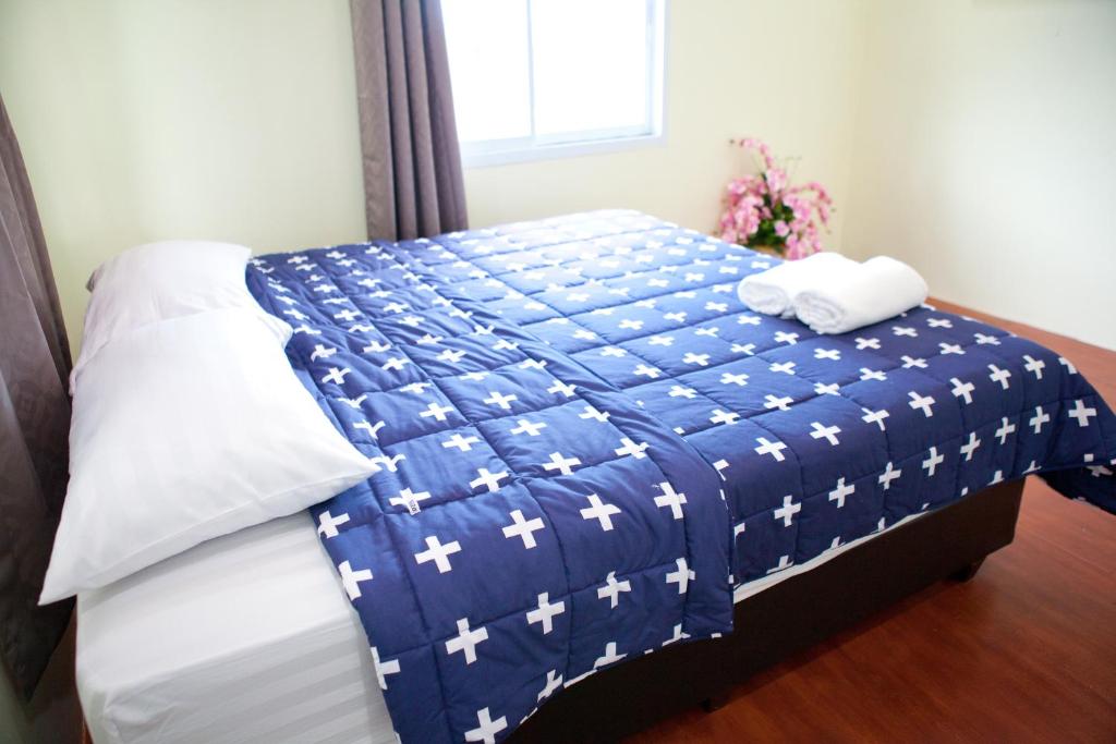 a bed with a blue and white blanket on it at Bannrommai Sattahip in Sattahip