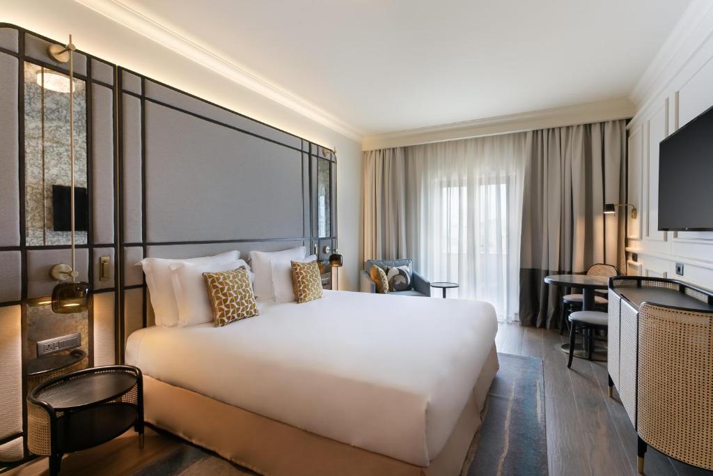 a hotel room with a large white bed and a desk at Kempinski Hotel San Lawrenz in San Lawrenz