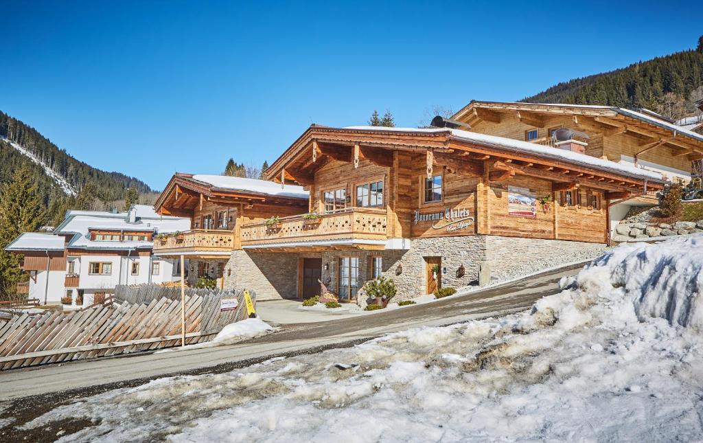 a large wooden house in the mountains with snow at Panorama Chalets in Saalbach Hinterglemm
