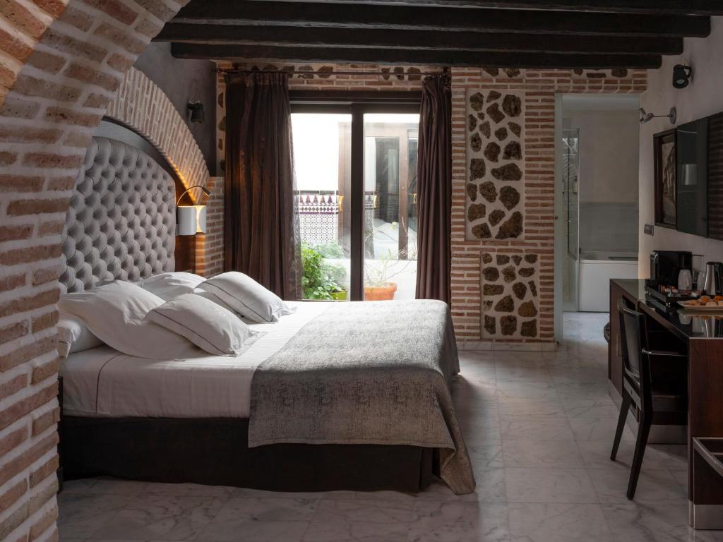 a bedroom with a bed and a brick wall at Pintor El Greco in Toledo