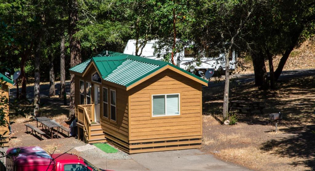 una pequeña casa con un techo verde en un patio en Russian River Camping Resort Cottage 7, en Cloverdale