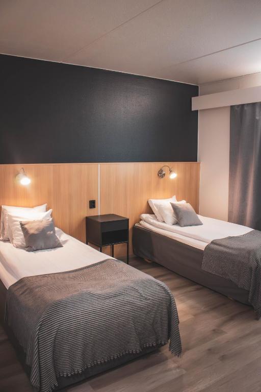 a hotel room with two beds and a black wall at Hotelli Puustelli Nivala in Nivala