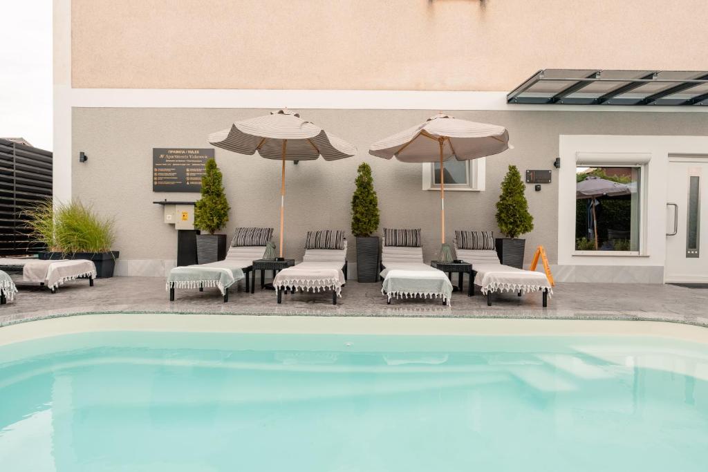 a pool with chairs and umbrellas next to a building at Apartments Vidanovic in Ohrid
