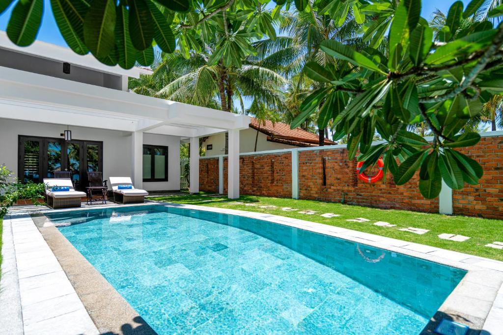a swimming pool in the backyard of a villa at RMH Le Belhamy Beach Resort in Hoi An