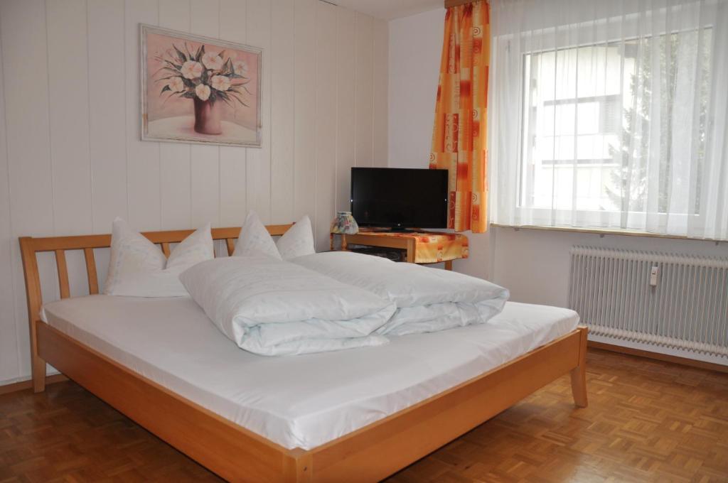 Schlafzimmer mit einem großen weißen Bett und einem TV in der Unterkunft Ferienwohnung Jenny in Schruns-Tschagguns