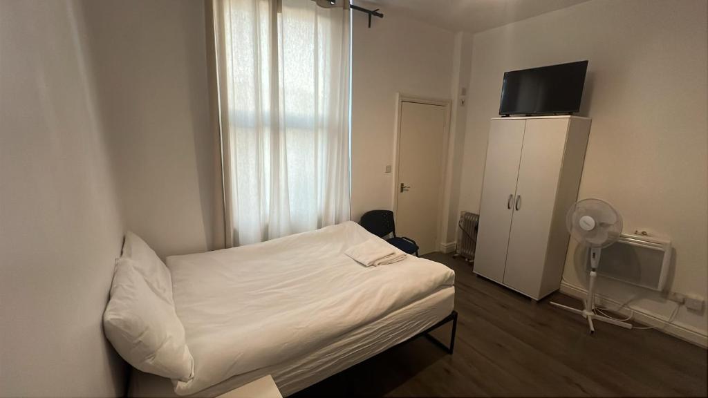 a small bedroom with a white bed and a tv at Spacious Studio on Wood Lane in London