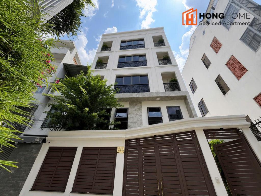 a white building with brown doors in front of it at HongHome Nguyễn Cửu Vân in Ho Chi Minh City