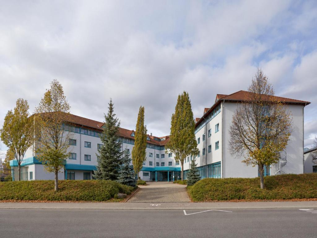 a large white building with trees in front of it at Sunday Hotel Stuttgart Herrenberg in Herrenberg