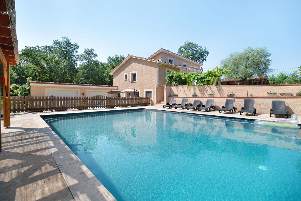 a swimming pool with chairs and a house at Appartement Type F4 in Maurens
