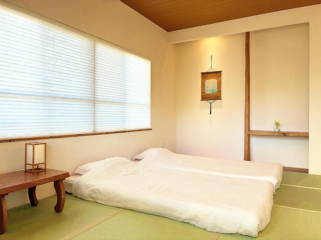 a bedroom with a white bed and a window at Guest House Ishigaki in Ishigaki Island