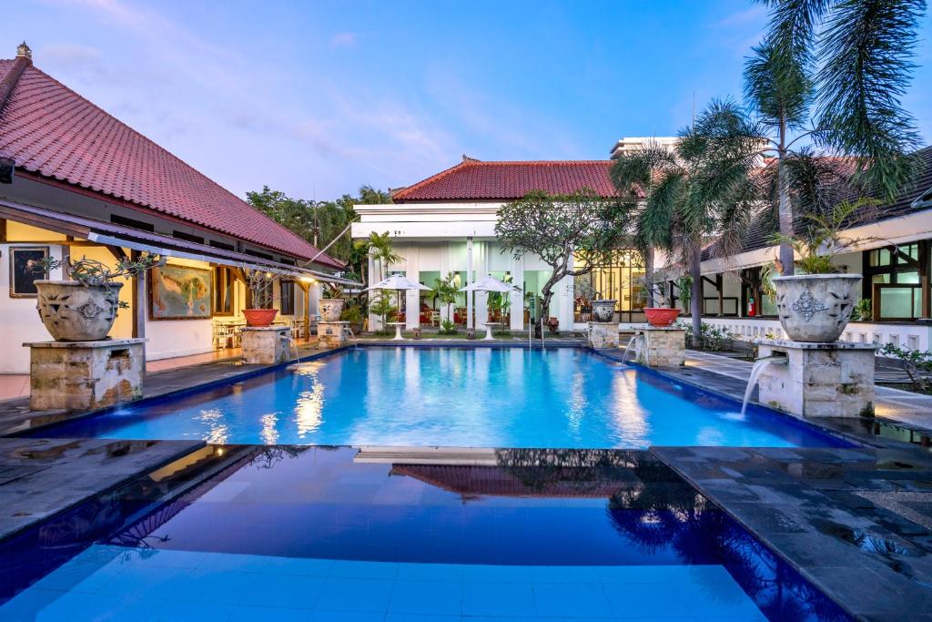 a swimming pool in front of a house at Inna Bali Heritage Hotel in Denpasar