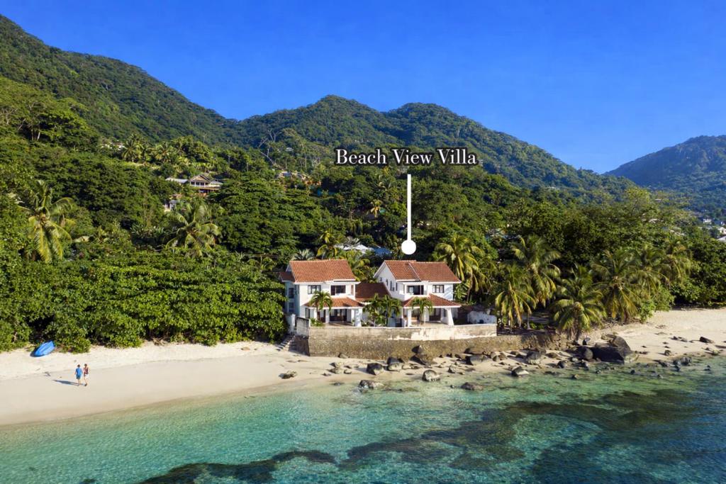 a house on a beach next to the ocean at Beach View Villa - Beauvallon villas in Beau Vallon
